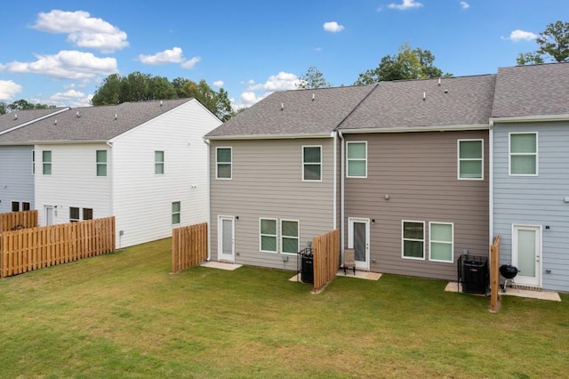 rear view of property with cooling unit and a lawn