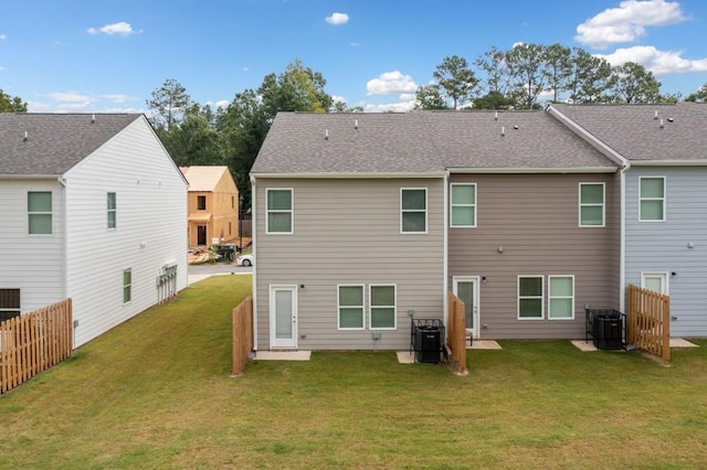 rear view of house featuring cooling unit and a yard