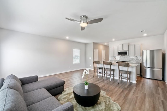 living room featuring ceiling fan, sink, and hardwood / wood-style floors