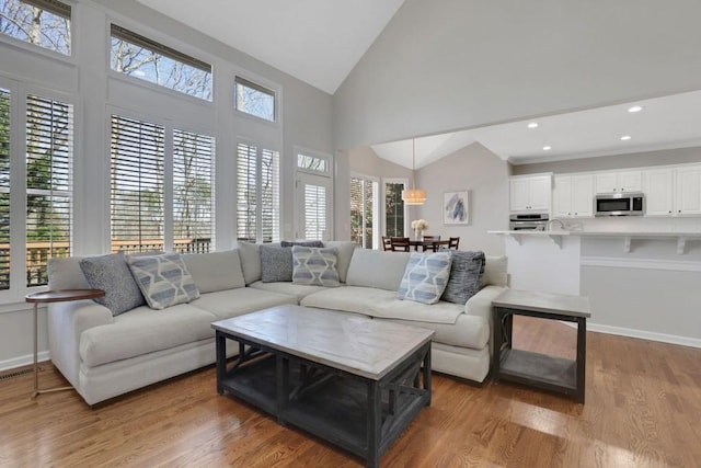 living area with visible vents, baseboards, wood finished floors, high vaulted ceiling, and recessed lighting