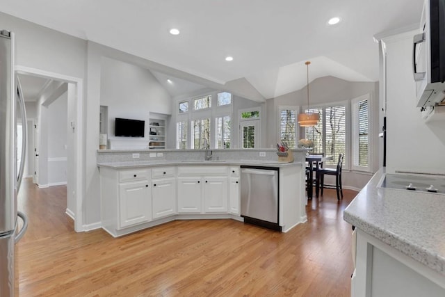 kitchen with vaulted ceiling, stainless steel appliances, a sink, and white cabinets