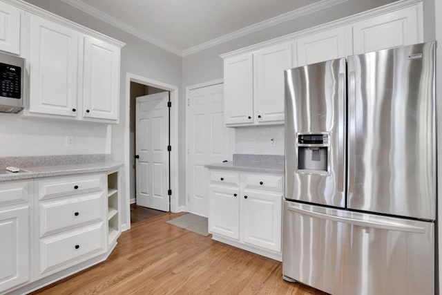 kitchen with light stone counters, light wood-style flooring, white cabinets, ornamental molding, and appliances with stainless steel finishes