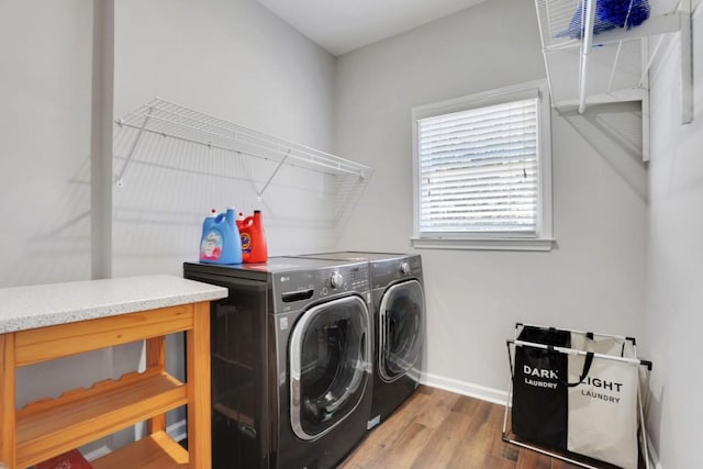 clothes washing area featuring laundry area, baseboards, washer and clothes dryer, and wood finished floors