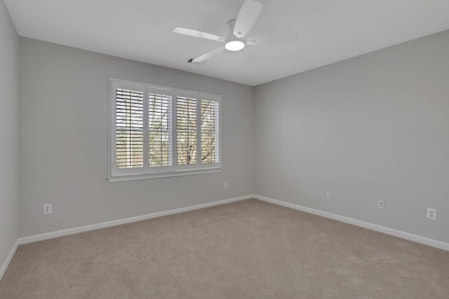 unfurnished room with a ceiling fan, light colored carpet, and baseboards