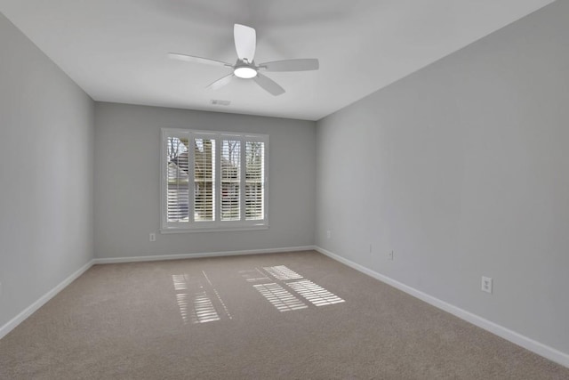 spare room featuring carpet floors, visible vents, and baseboards