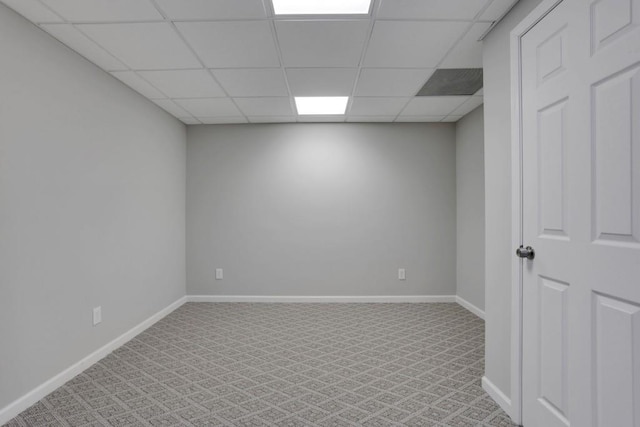 basement featuring light carpet, a paneled ceiling, and baseboards