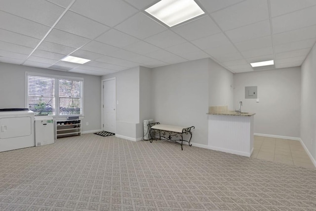 below grade area featuring baseboards, a drop ceiling, washer / dryer, and light colored carpet