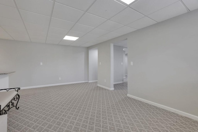 basement with baseboards, a drop ceiling, and light colored carpet