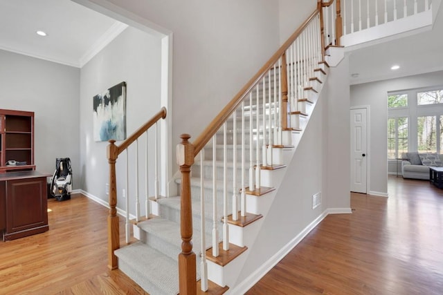 stairway with recessed lighting, a towering ceiling, baseboards, and wood finished floors