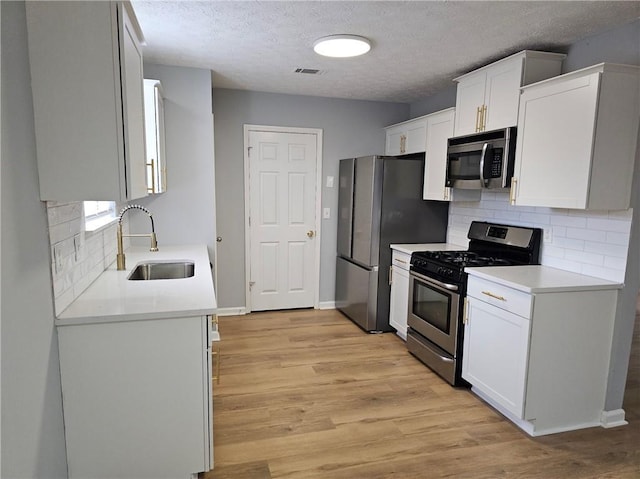 kitchen featuring a sink, visible vents, white cabinetry, appliances with stainless steel finishes, and light wood-type flooring