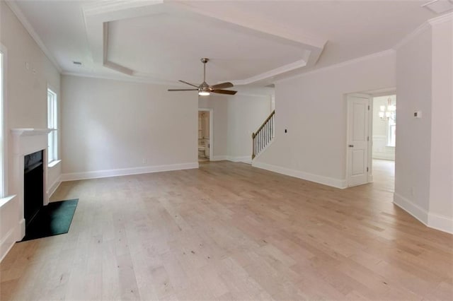 unfurnished living room featuring stairs, light wood-style floors, a fireplace, and crown molding