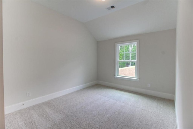 unfurnished room featuring baseboards, visible vents, vaulted ceiling, and carpet flooring