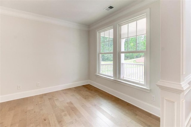 empty room featuring ornamental molding, visible vents, light wood-style floors, and baseboards