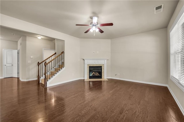 559 Myrle Trace Ln, Suwanee, GA 30024 - unfurnished living room featuring a ceiling fan, dark wood-style flooring, a tile fireplace, stairway, and healthy amount of natural light