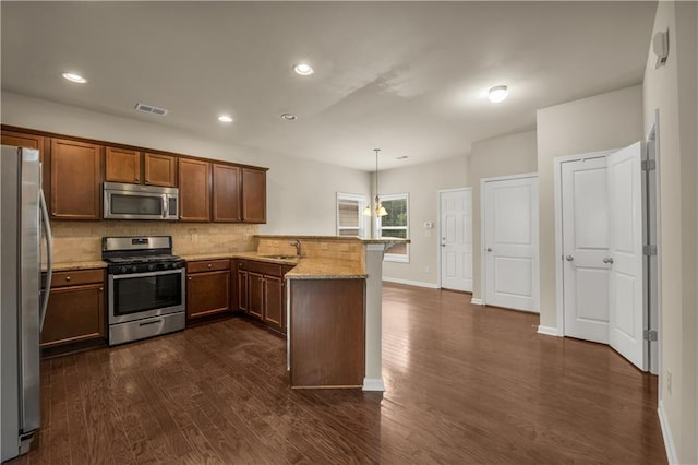 559 Myrle Trace Ln, Suwanee, GA 30024 - kitchen featuring appliances with stainless steel finishes, a sink, a peninsula, dark wood-type flooring, and tasteful backsplash