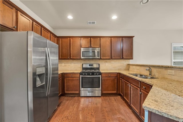 559 Myrle Trace Ln, Suwanee, GA 30024 - kitchen featuring appliances with stainless steel finishes, a sink, dark wood finished floors, backsplash, and light stone counters