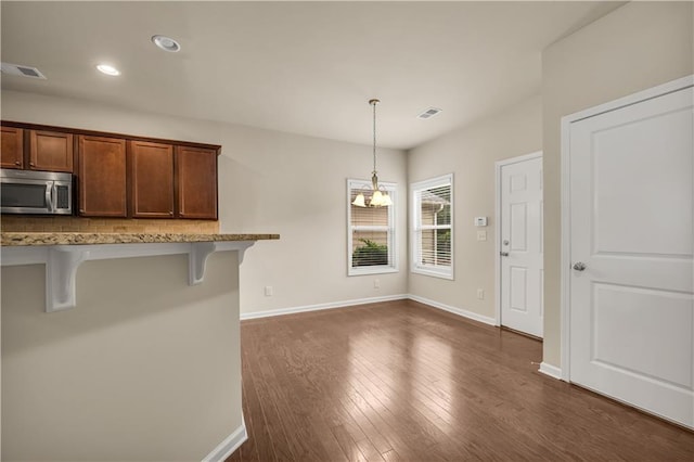559 Myrle Trace Ln, Suwanee, GA 30024 - kitchen with stainless steel microwave, a breakfast bar area, decorative light fixtures, dark wood-type flooring, and recessed lighting