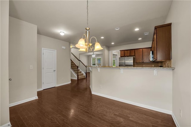 559 Myrle Trace Ln, Suwanee, GA 30024 - kitchen with appliances with stainless steel finishes, light stone countertops, dark wood-type flooring, a kitchen bar, and a peninsula