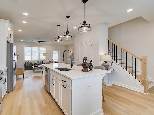 kitchen with light wood-style floors, open floor plan, appliances with stainless steel finishes, and a sink