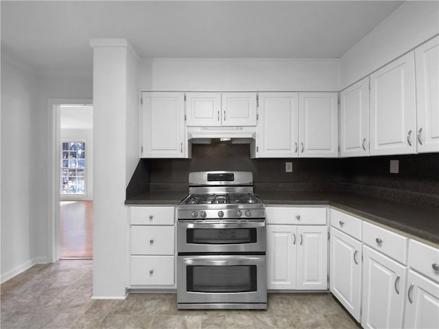 8005 Bamby Ln, Jonesboro, GA 30236 - kitchen with under cabinet range hood, white cabinets, double oven range, decorative backsplash, and dark countertops