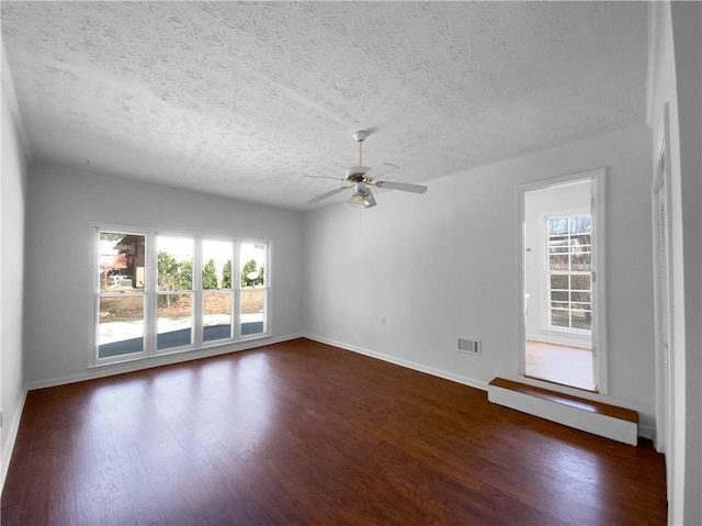 8005 Bamby Ln, Jonesboro, GA 30236 - spare room with visible vents, dark wood finished floors, a ceiling fan, baseboard heating, and a textured ceiling