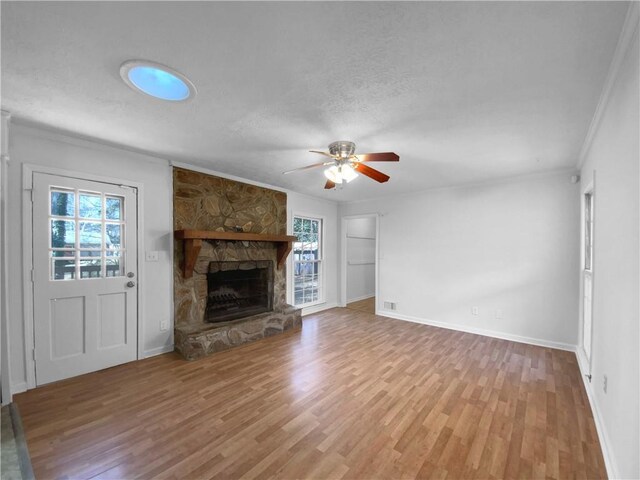 8005 Bamby Ln, Jonesboro, GA 30236 - unfurnished living room featuring a ceiling fan, wood finished floors, a stone fireplace, crown molding, and a textured ceiling