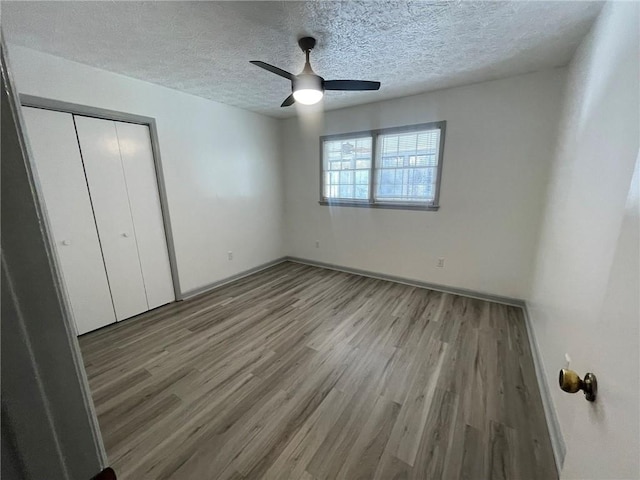 unfurnished bedroom with a textured ceiling, ceiling fan, a closet, and light hardwood / wood-style flooring