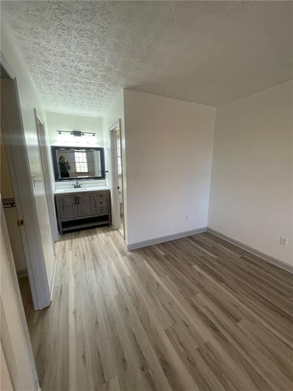 unfurnished living room featuring a textured ceiling and light hardwood / wood-style flooring