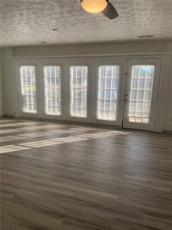 unfurnished room featuring ceiling fan, french doors, dark hardwood / wood-style floors, and a textured ceiling