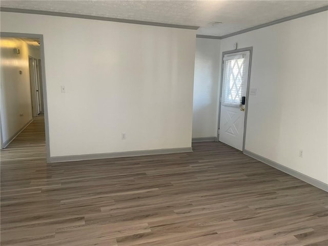 unfurnished room with a textured ceiling, dark hardwood / wood-style flooring, and ornamental molding