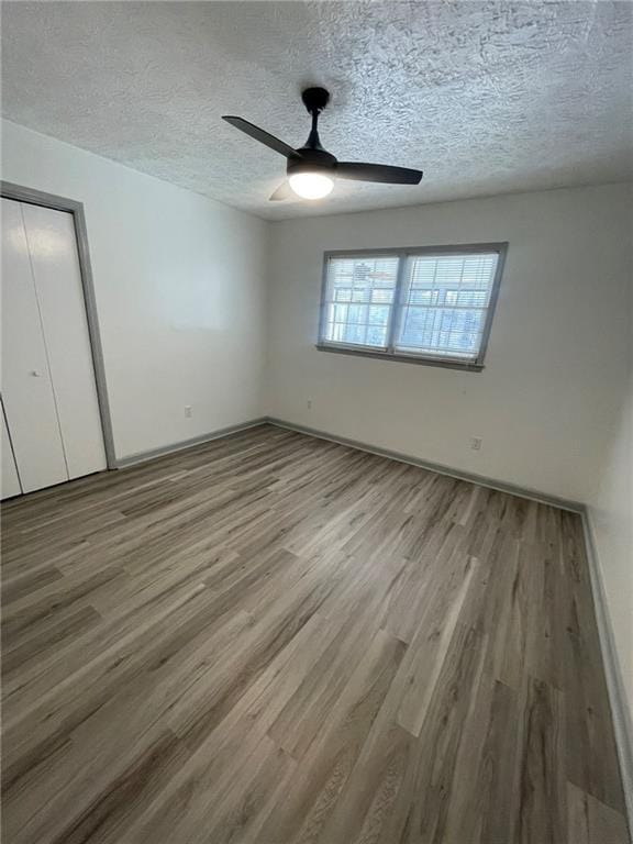 unfurnished bedroom featuring ceiling fan, wood-type flooring, and a textured ceiling