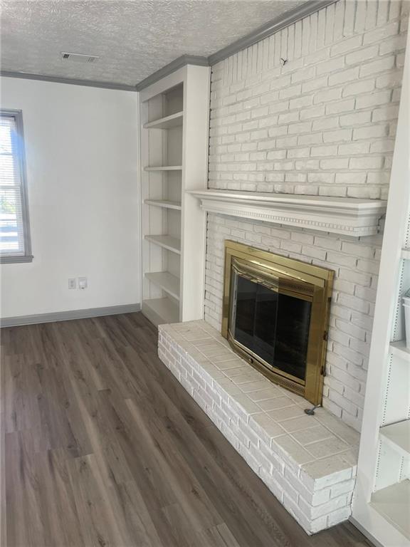 unfurnished living room featuring a textured ceiling, dark hardwood / wood-style flooring, crown molding, and a fireplace