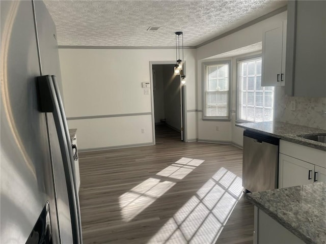 unfurnished dining area featuring a textured ceiling, dark wood-type flooring, and crown molding