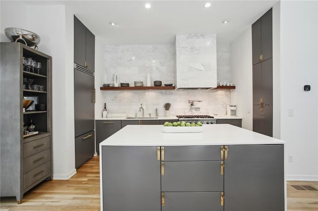 kitchen with stainless steel appliances, a center island, light hardwood / wood-style flooring, and gray cabinetry