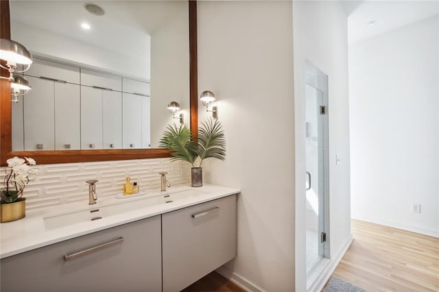 bathroom with vanity, wood-type flooring, backsplash, and a shower with shower door