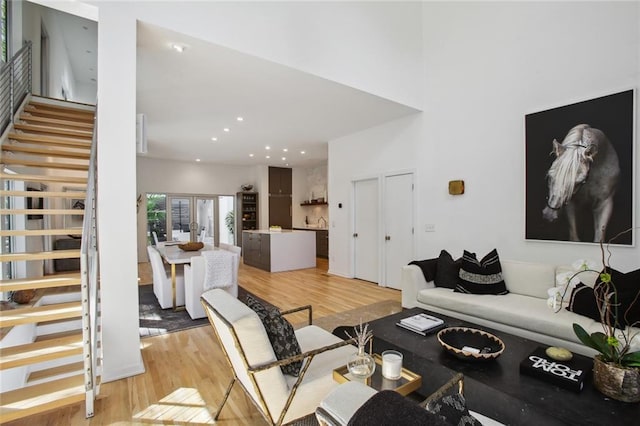 living room with a towering ceiling and light wood-type flooring