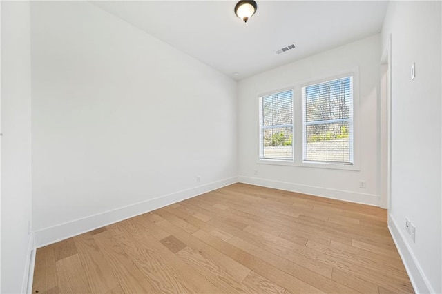 unfurnished room with visible vents, light wood-style flooring, and baseboards