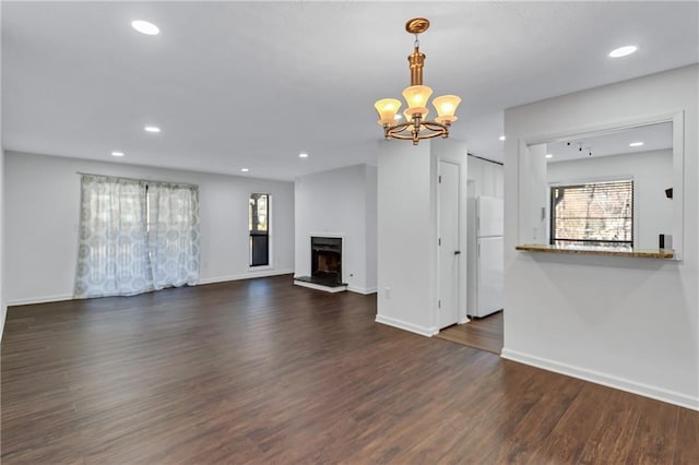 unfurnished living room featuring dark hardwood / wood-style flooring and an inviting chandelier