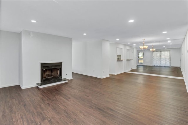 unfurnished living room featuring an inviting chandelier and dark hardwood / wood-style flooring