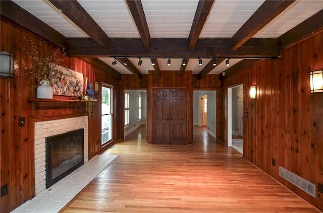 970 Winding Creek Trl, Sandy Springs, GA 30328 - unfurnished living room featuring rail lighting, wooden walls, light wood-style flooring, beamed ceiling, and a brick fireplace