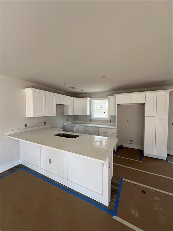 kitchen with white cabinets, kitchen peninsula, and sink