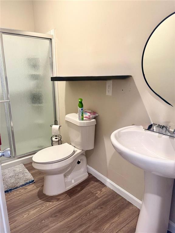 bathroom featuring wood-type flooring, toilet, and a shower with door