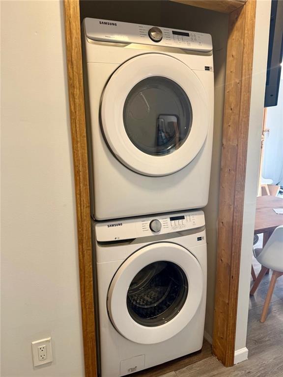 washroom with stacked washing maching and dryer and hardwood / wood-style floors