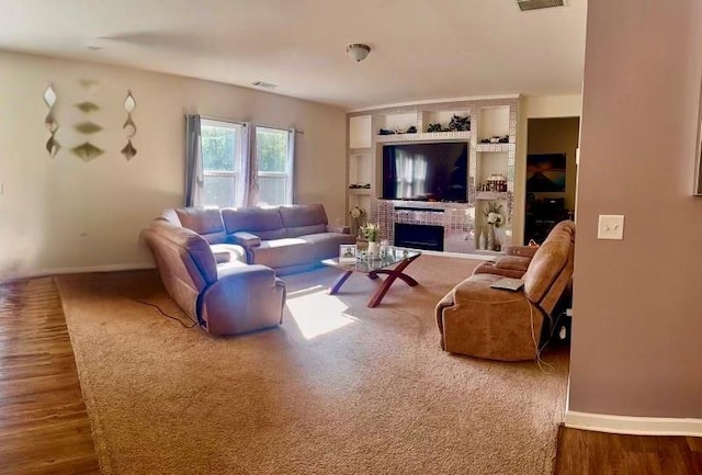 living room with hardwood / wood-style flooring, built in features, and a fireplace