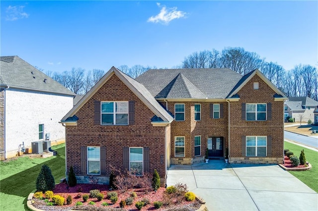 view of front facade featuring brick siding, central AC, a front lawn, and roof with shingles