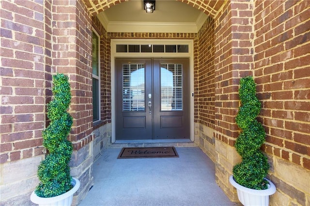 view of exterior entry featuring french doors and brick siding