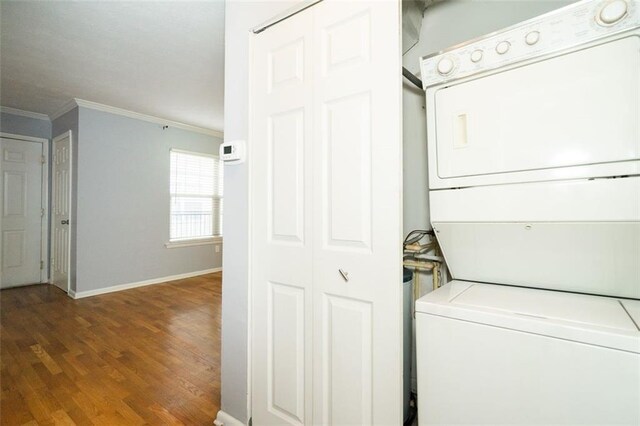 laundry room featuring hardwood / wood-style flooring, crown molding, and stacked washer and dryer