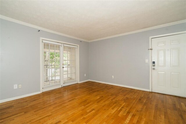 spare room featuring wood-type flooring and crown molding