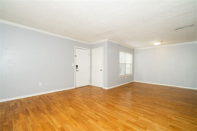 empty room with ornamental molding and light hardwood / wood-style floors