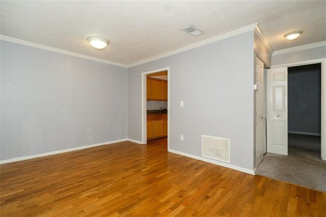 empty room with ornamental molding and wood-type flooring